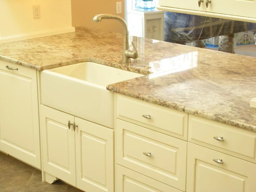 Light stone counters and farmhouse sink in a cream cabinet kitchen